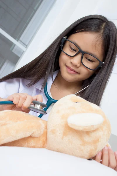Asian girl playing as a doctor with stethoscope and bear doll