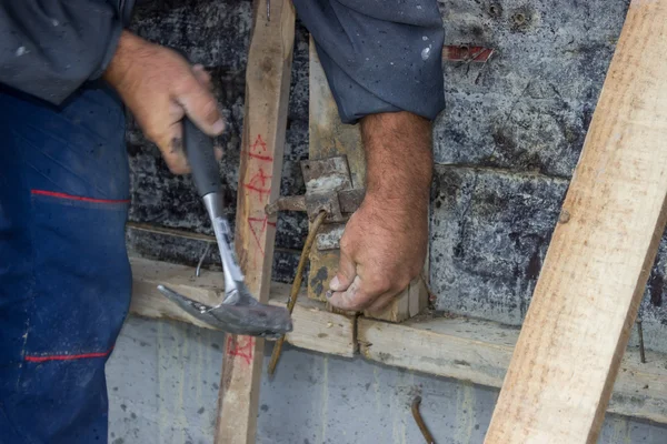 Builder hammering a nail into a piece of wood 5