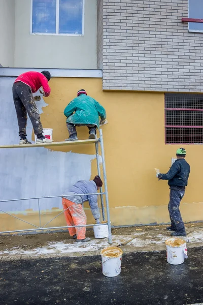 Builder workers plastering facade