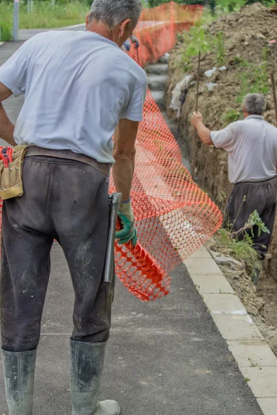 Construction workers set orange safety fence 3