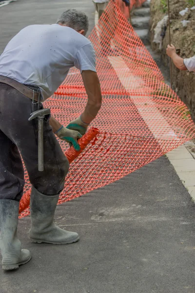 Construction workers set orange safety fence 4
