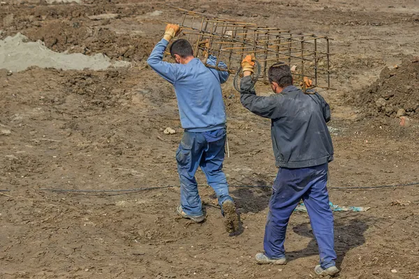 Workers carrying reinforcing rod for a concrete column