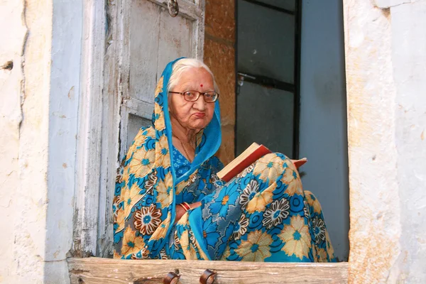 16.10.2012 - Jaisalmer. Rajasthan, India. Elderly woman reading a book on his doorstep.