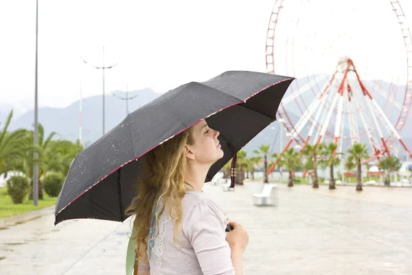 Beautiful young blond woman walking around the city in the rain
