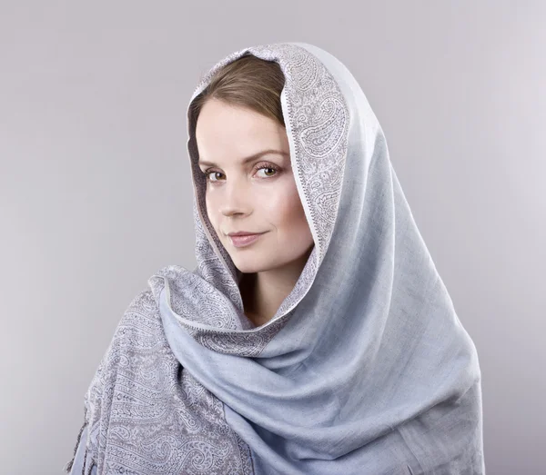Lovely young blonde in a pale blue scarf on her head on gray background
