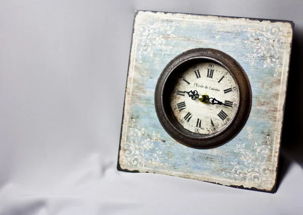Blue clock in the style of Provence on the gray fabric. Vintage watches. yellow candle