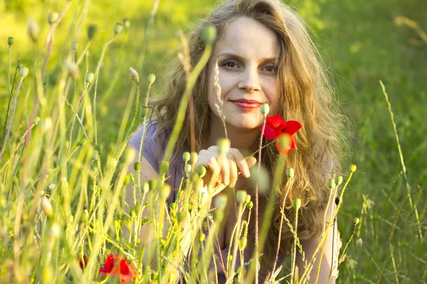 Beautiful happy girl enjoying the sun in the poppy fields. Woman outdoors. Sunrays in the hair. Country style. Flower Fields. Free happy woman