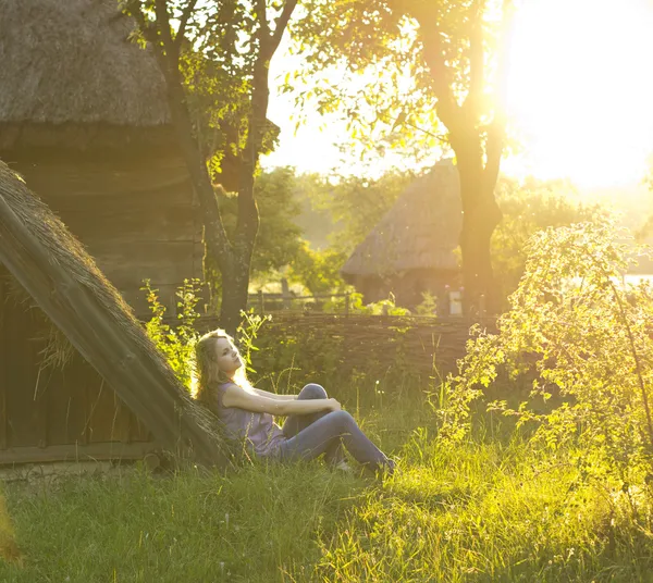 Beautiful curly blonde enjoys the sun in the countryside. Sunrays in the hair. Country style. Country house. perfect weather.