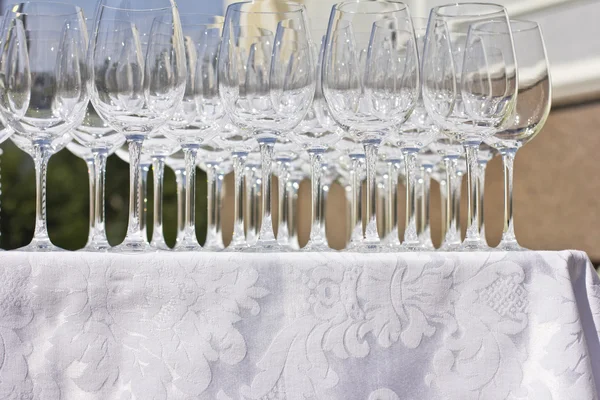 Wedding glasses on the white silk tablecloth, on the street. sunny weather. wedding preparations.