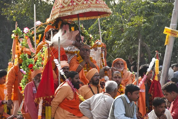 Indian sadhu follows down street in entourage of devotees and pilgrims during celebration festival Kumbha Mela in Haridwar, India.