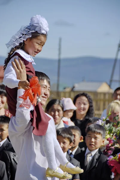 Senior student carries young school girl on traditional ceremony on September 1 in Ivolginskoe Village, Buryatia, Russia.