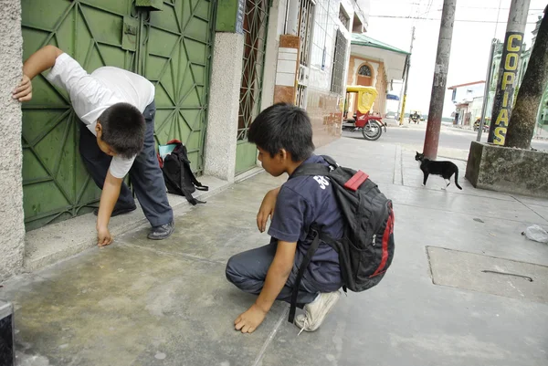 Peruvian school boys play with coins on a street in Iquitos, Peru.