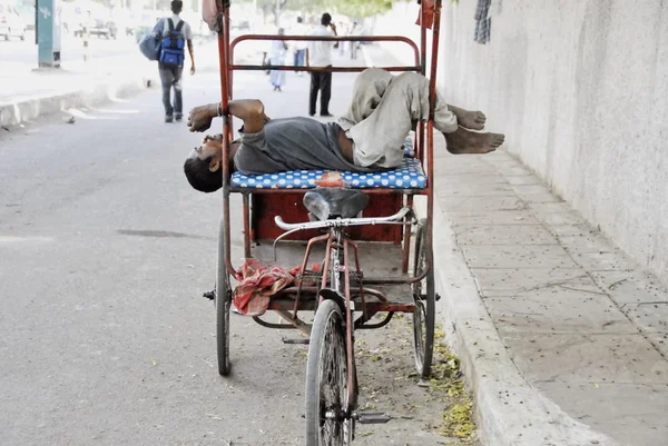 Rickshaw man rests on his rikshaw in Delhi, India.
