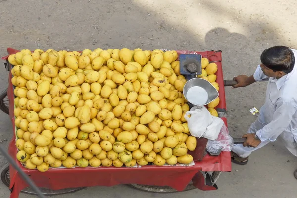 Street vendor pushes his cart full of mangoes in New Delhi, India.