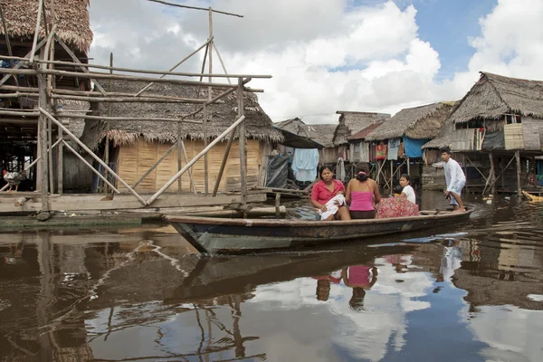 Peruvian family in traditional boat float on water street in Belen, Iquitos, Peru.