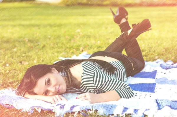 Young woman laying down on the ground in autumn park