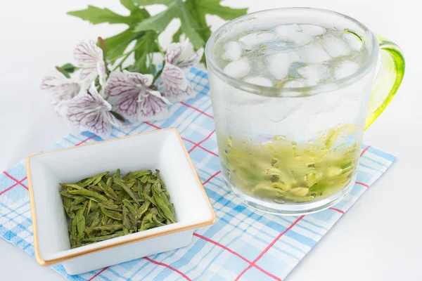 Green tea with ice in the glass and green tea leaves with flowers