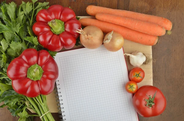 Grocery shopping list with notebook and fresh vegetables