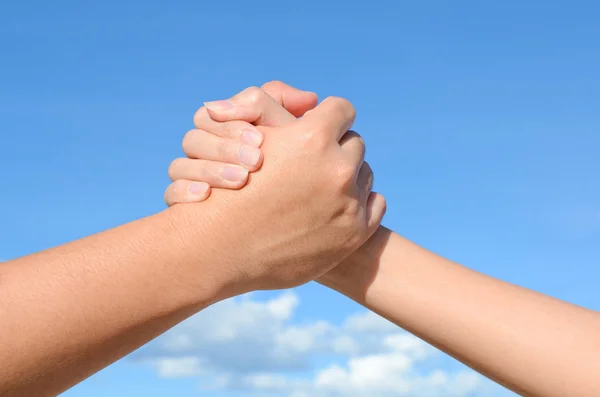 Partner hand between a man and a woman on blue sky background, Teamwork
