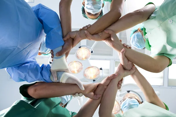Small group of doctor team joining hands, ant\'s eyes angle view.