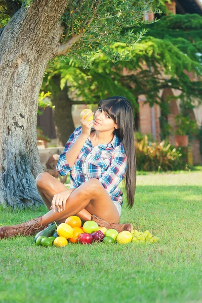 Beautiful woman on the green grass eaten fruits
