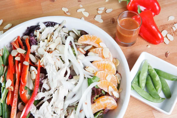 Colorful large serving of Spicy Asian themed chicken and citrus salad with nuts, peppers, fruit and vegetables