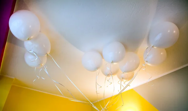 White balloons in yellow room