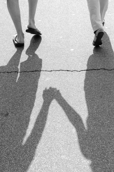 Black and white photo of shadow of a couple walking on a street