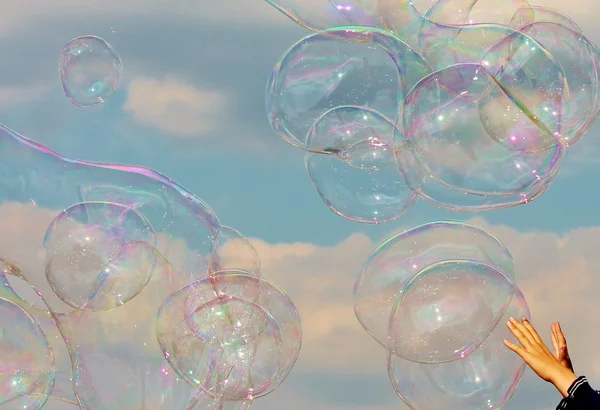 Childs hands reaching for giant soap bubbles
