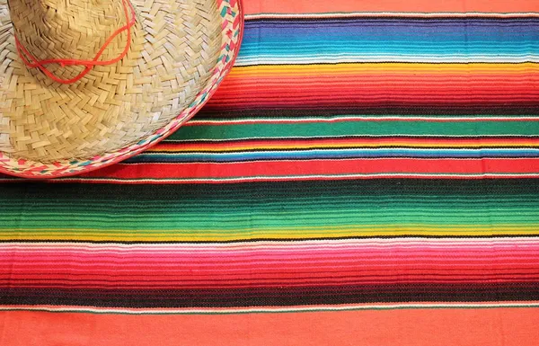 Fiesta mexican poncho rug in bright colors with sombrero background with copy space