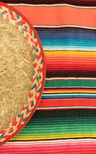 Fiesta mexican poncho rug in bright colors with sombrero background with copy space