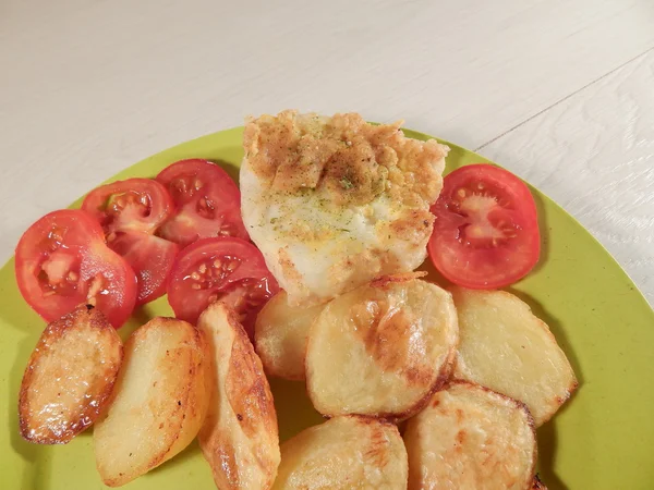 Baked potato and grilled white fish on a bamboo plate, wooden table