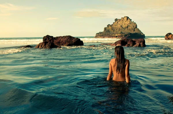 Back of a young woman in the sea water