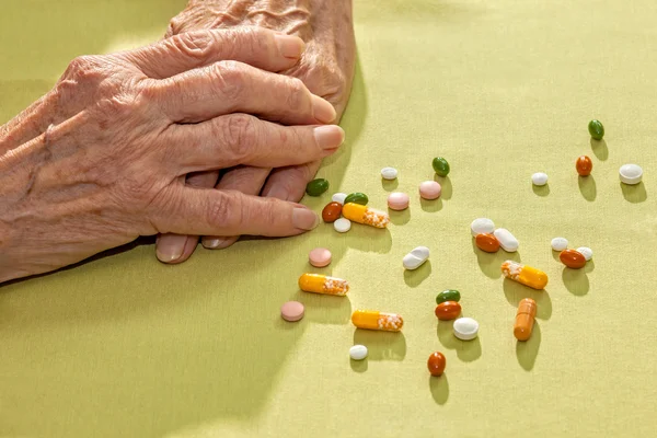 Clasped hands of an elderly lady alongside medication