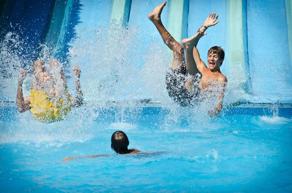 Young people having fun on water slides in aqua park