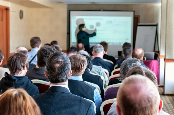 Business conference. people sitting rear and speaker explaining