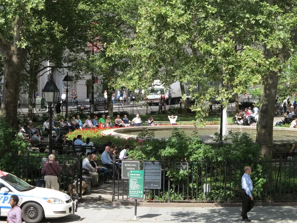 New York City Police Car sits idle while people enjoy a summer day at Bowling Green Park in New York