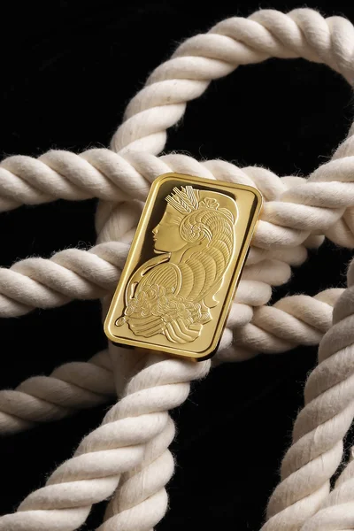 Gold ingot on white rope