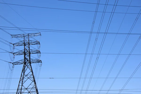 Electricity Pylon With Power Cables Against Blue Sky