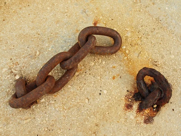 Extreme corrosion of chain link fixed in concrete block. Salt spray corrosion of iron chain in sea port.