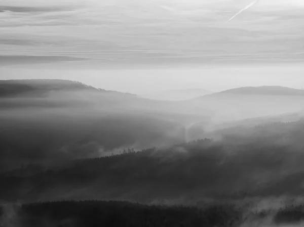 Autumn sunrise in a beautiful mountain of Bohemia. Peaks of hills increased from fog.