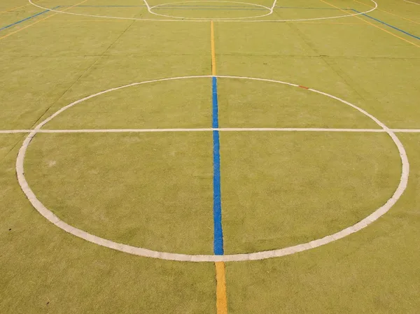 Empty outdoor hanball playground, plastic light green surface on ground and white blue bounds lines.