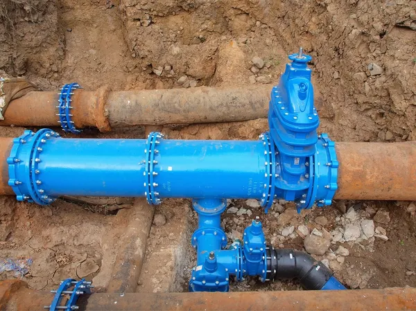 Old big drink water pipes joined with new blue valves and new blue joint members. Finished repaired piping waiting for covering by clay. Extreme kind of corrosion, metal corroded texture.