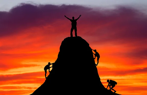 Man on top of the mountain and the other people to climb up. Spo