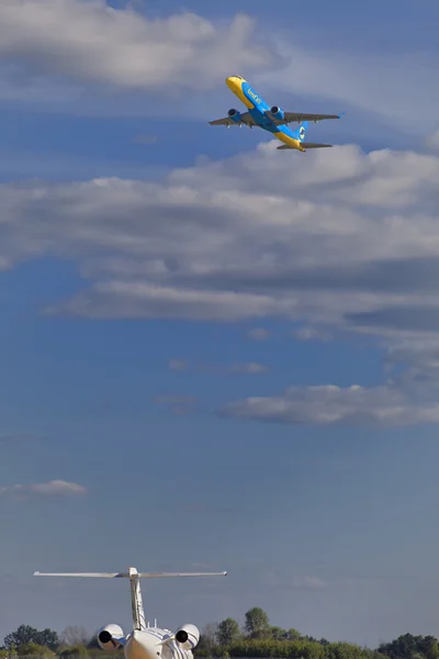 Large commercial airplane taking off, small jet is waiting to take off