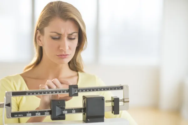 Woman Using Balance Weight Scale At Gym