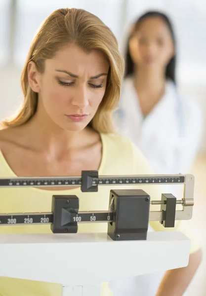 Woman Weighing Herself On Balance Weight Scale At Clinic