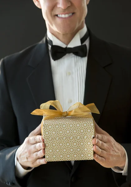 Midsection Of Happy Man In Tuxedo Holding Gift Box