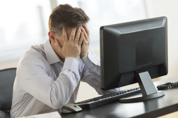 Stressed Businessman Leaning On Computer Desk