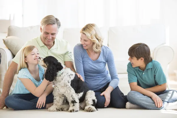 Girl Playing With Dog While Family Looking At Her